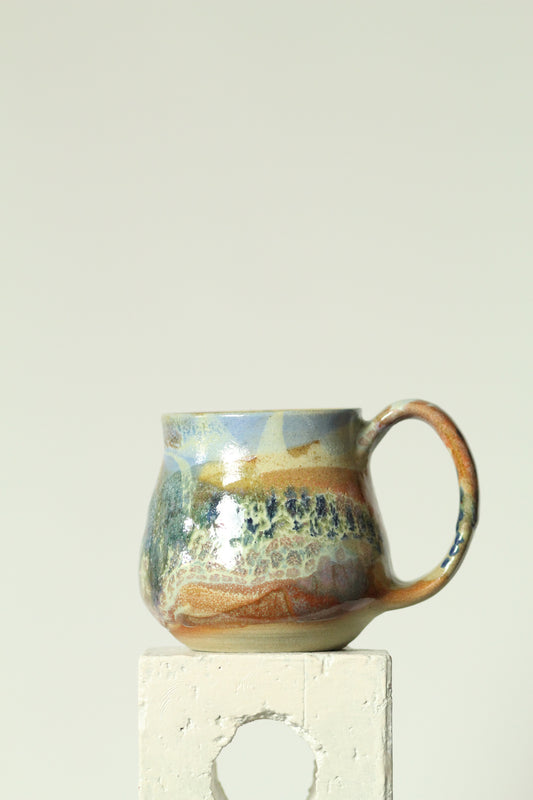 Handmade ceramic mug with a textured surface on a plain background