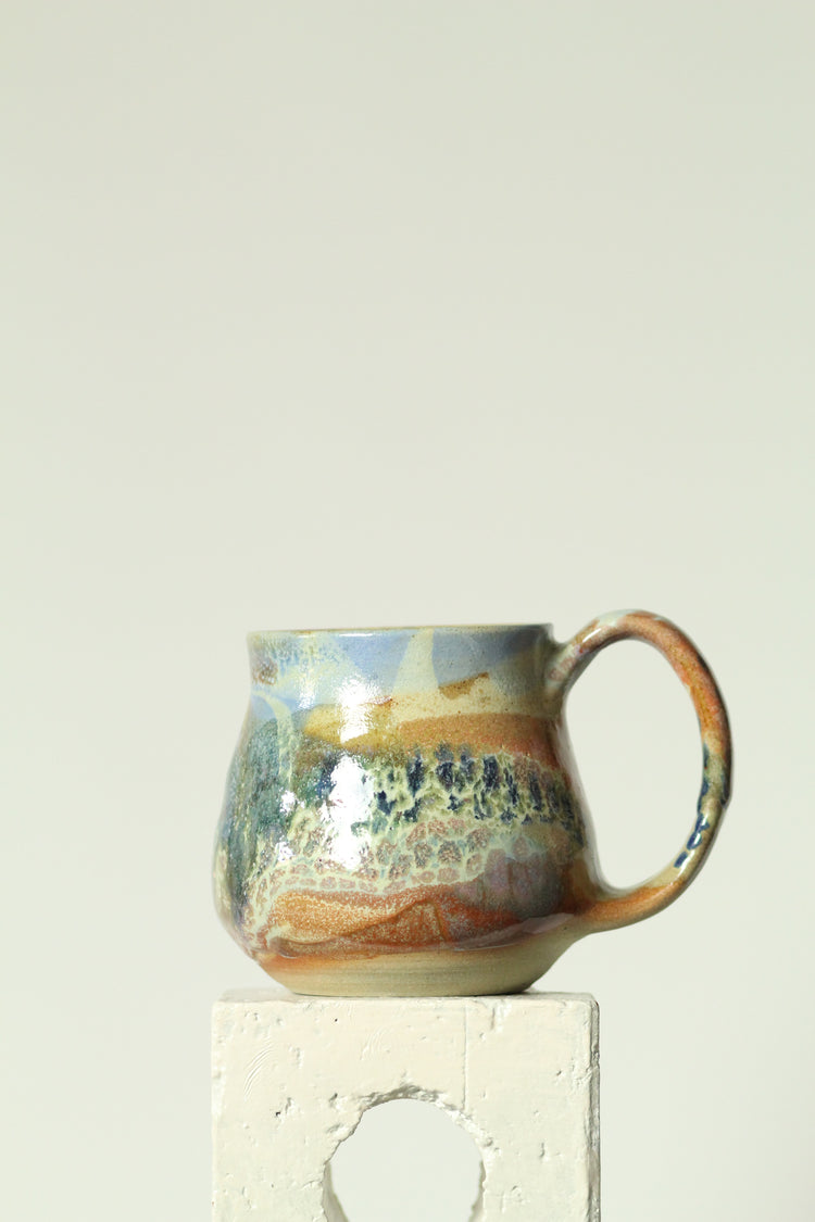 Handmade ceramic mug with a textured surface on a plain background