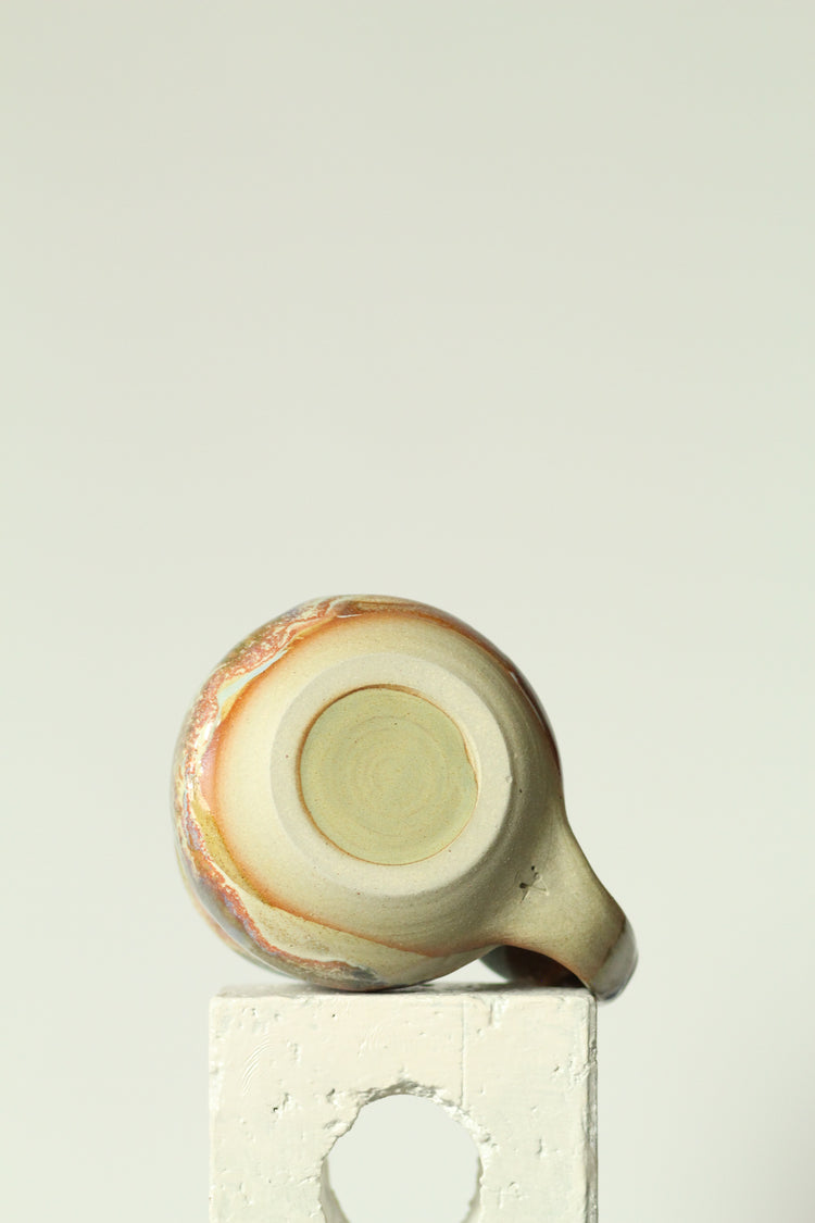 Ceramic mug base with a decorative pattern on a plain background