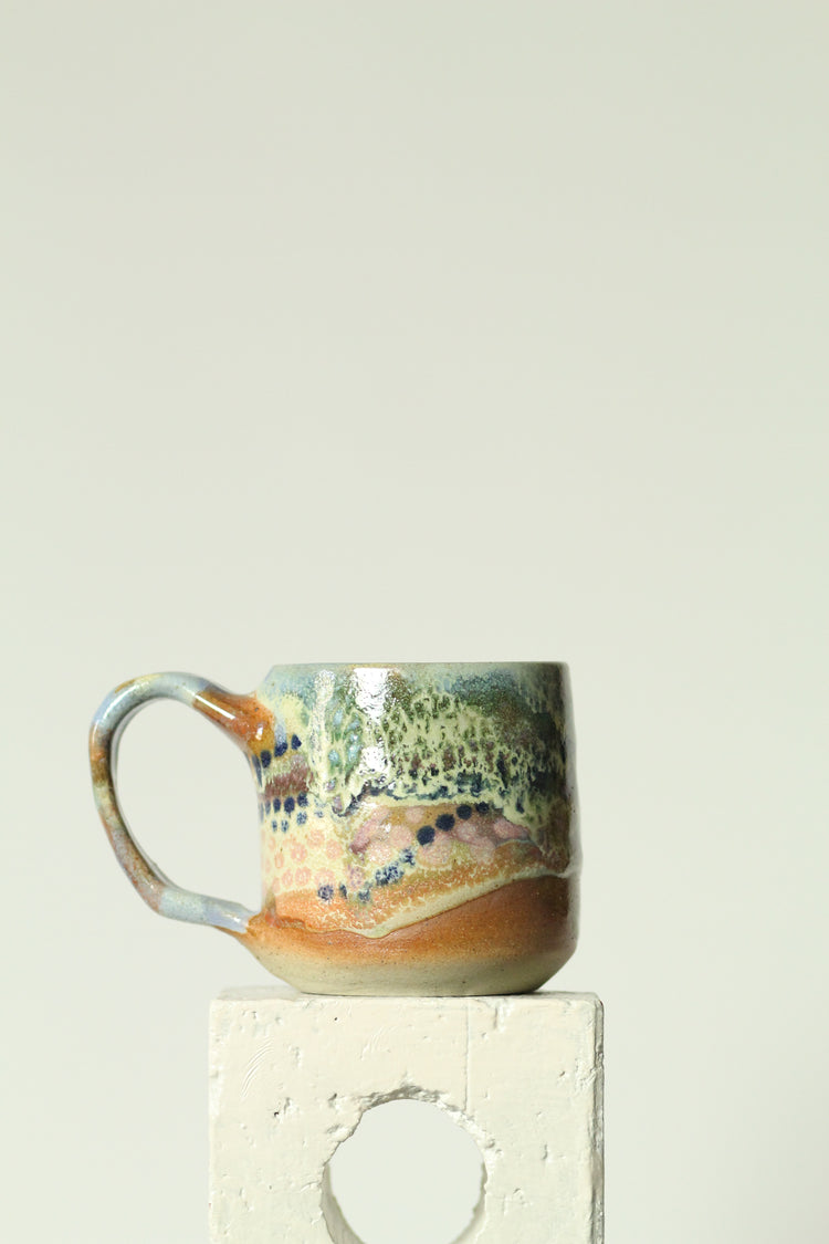 Ceramic mug with multicolored glaze on a beige background
