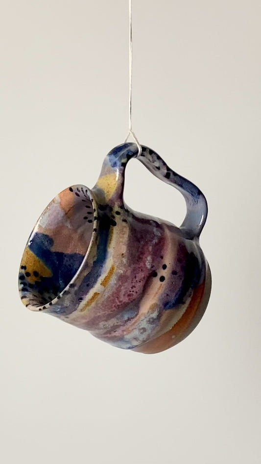 Handmade ceramic mug in the Body form with Imprint handle detail, finished in painterly Dusk glaze with layered blues, violet and warm clay tones. spinning to see full mug
